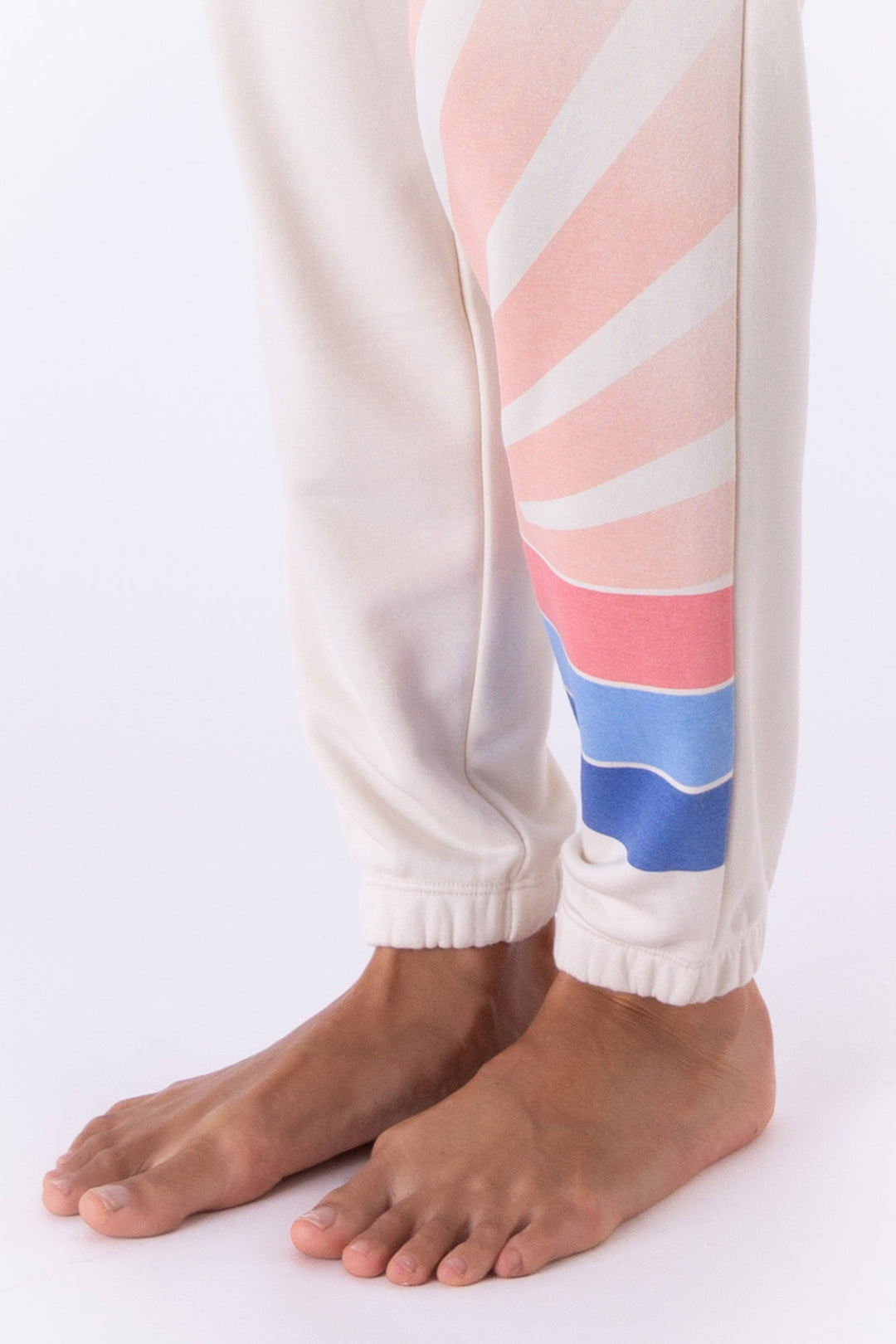 Ivory French Terry jogger pant with striped sunrise printed on left leg. Side pockets.