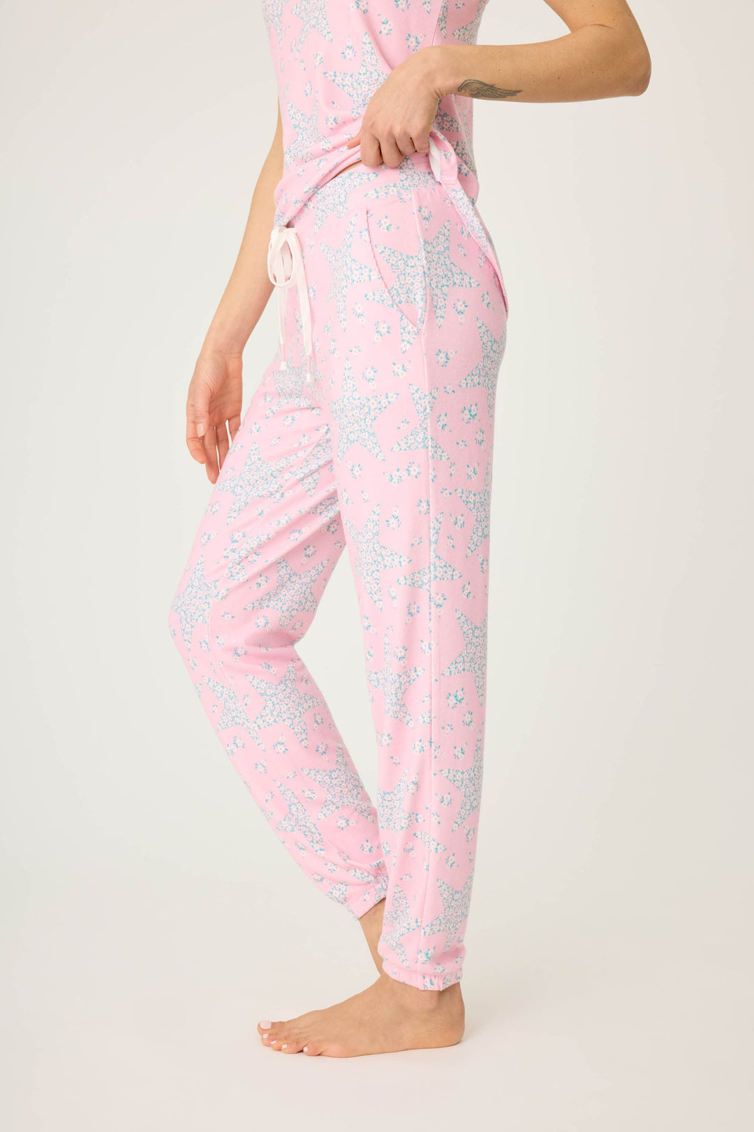 Women's pink & star print jogger pant with pockets in peachy jersey. Tie waist & banded hem. Scallop edge trim at pocket openings.
