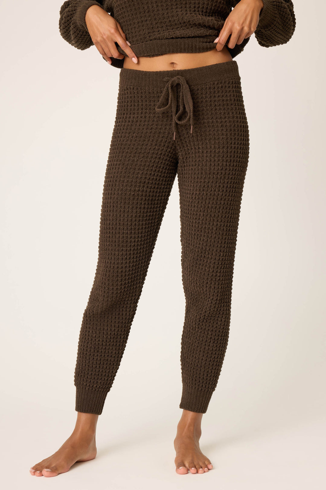 A person wearing P.J. Salvage's Chenille Waffle Solid Chocolate Banded Pant stands barefoot against a plain light background, with their torso and head partially out of frame.