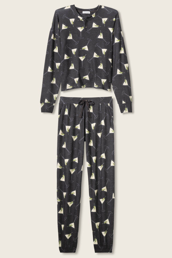 The Merrier With A Martini PJ Set by P.J. Salvage features a long-sleeve top and drawstring pants in dark fabric with an all-over martini glass print, displayed flat on a light background.