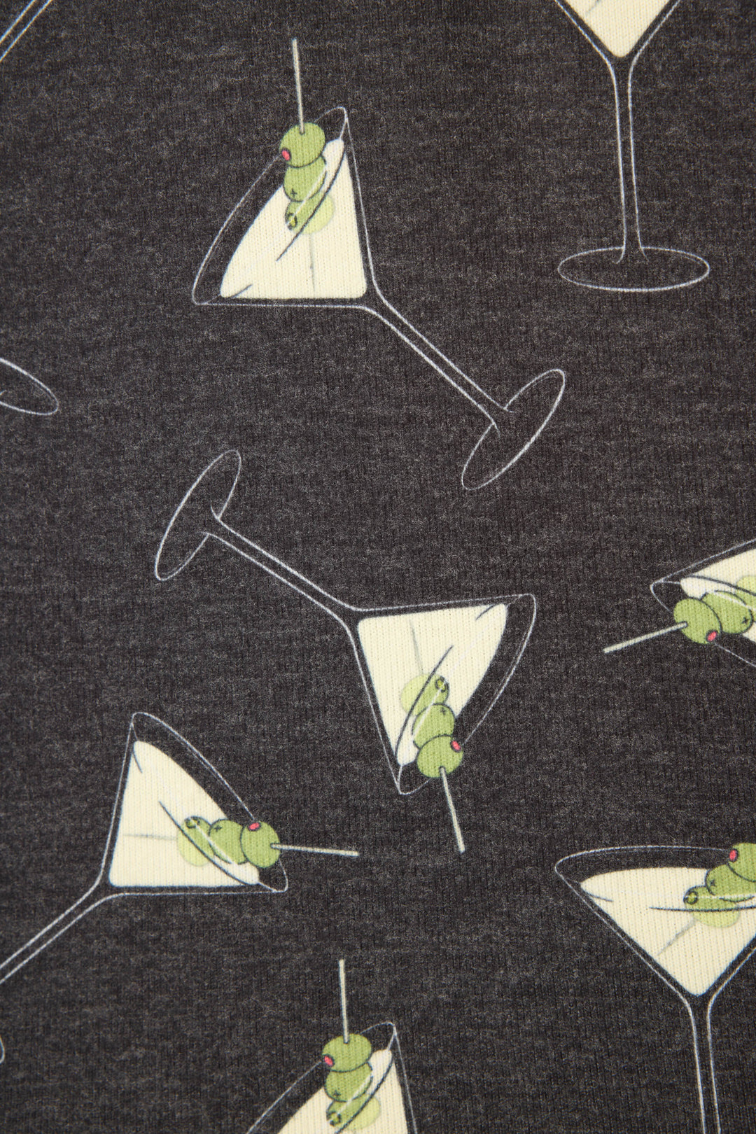 The P.J. Salvage Merrier With A Martini PJ Set features dark grey fabric with a playful pattern of martini glasses and green olives on toothpicks, shown both upright and tilted at various angles.