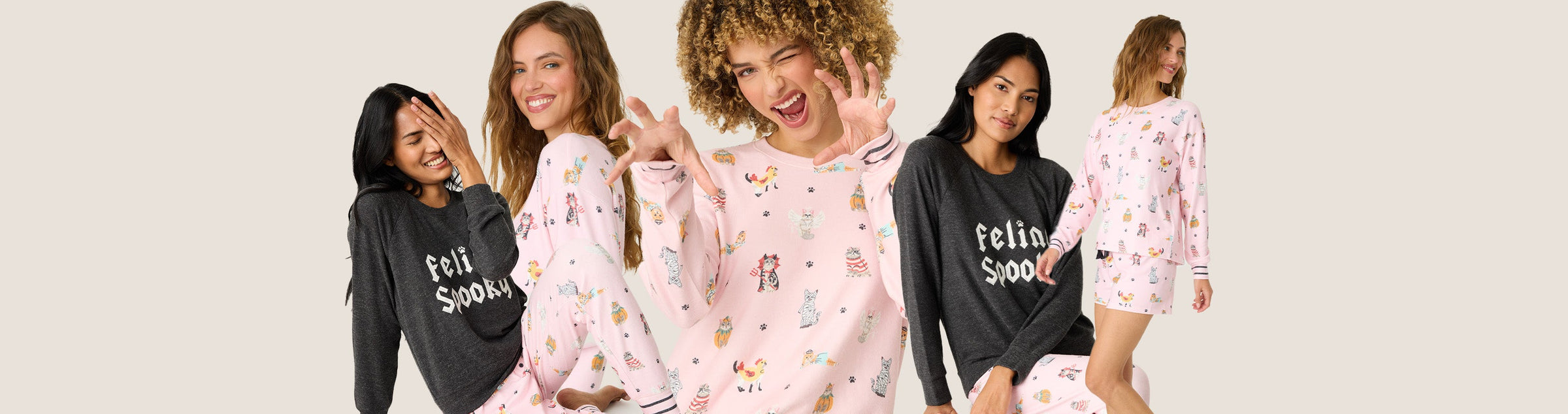 Five women pose wearing pajama sets; two sets are dark with “Feeling Spooky” text, and three are light pink with colorful, playful illustrations. The background is a solid light beige.