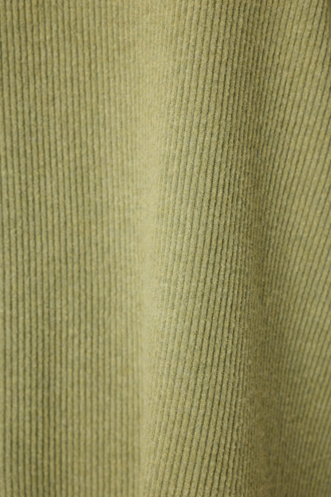 Close-up of soft, textured light green corduroy fabric with vertical ridges.