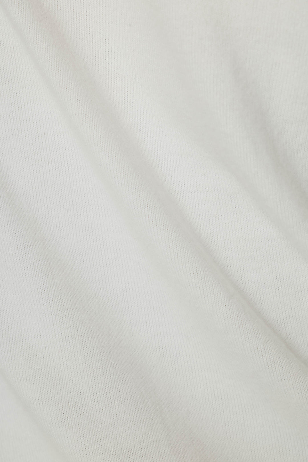 A close-up of a white ribbed knit fabric texture with soft folds.