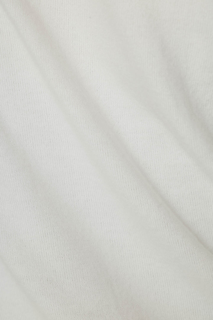 A close-up of a white ribbed knit fabric texture with soft folds.