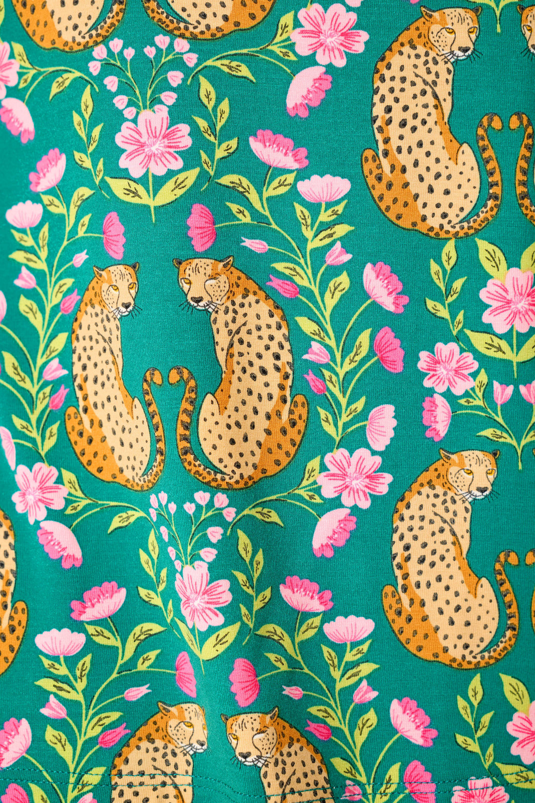 Cheetahs with black spots sit gracefully among pink flowers and green leaves in a repeating pattern on a bright teal background.