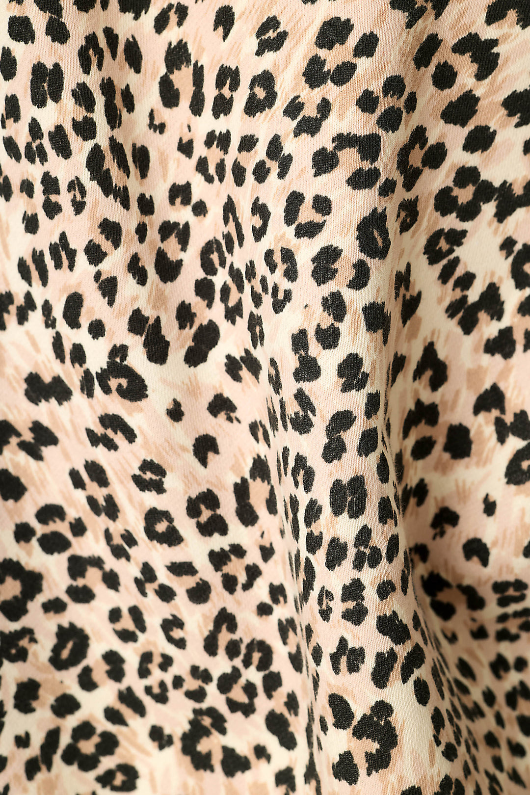 Close-up of a leopard print fabric with black irregular spots on a light beige background.