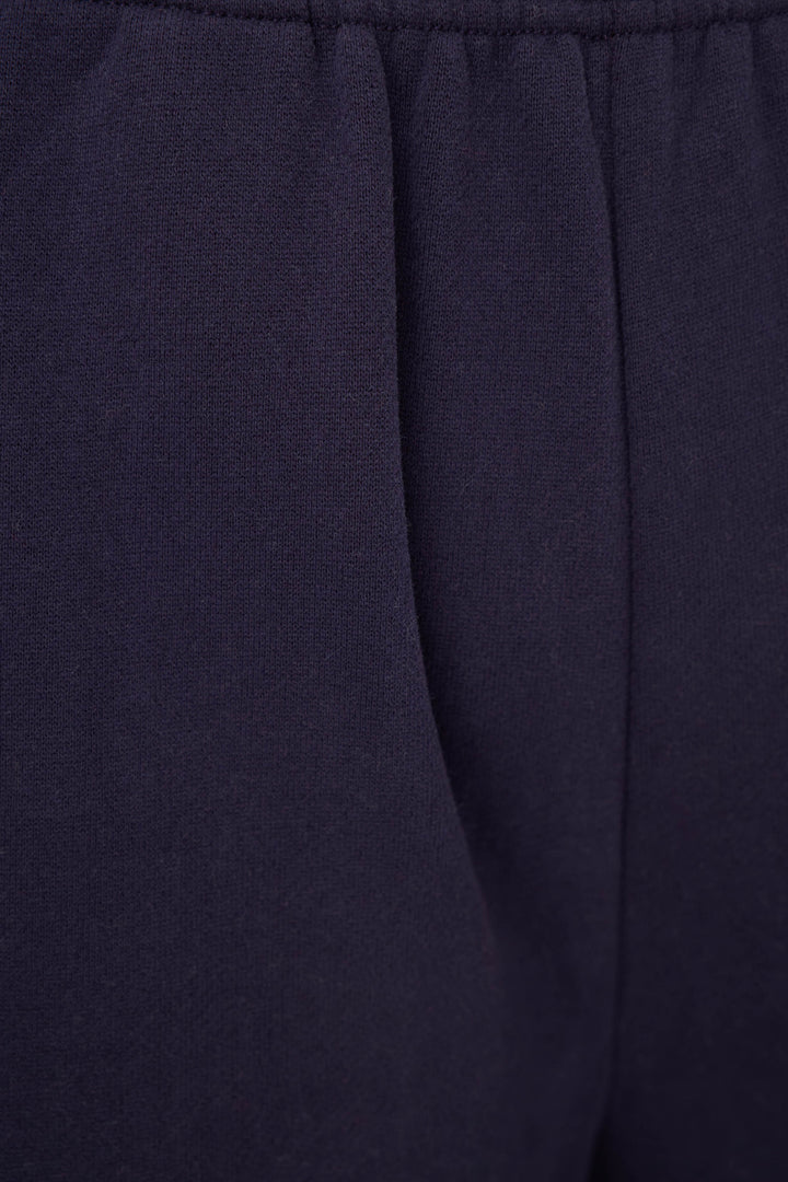 Close-up of dark navy fabric with a gathered waistband and vertical seam detail.