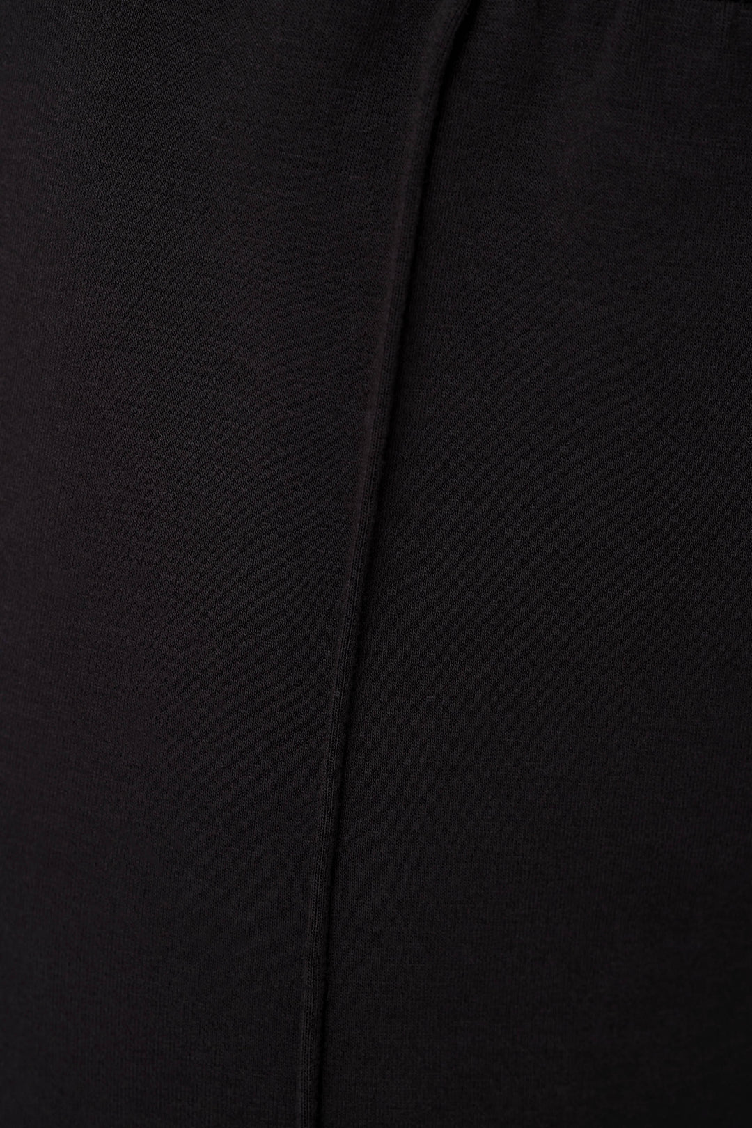 Close-up of a black fabric surface with a vertical seam or fold running down the center.