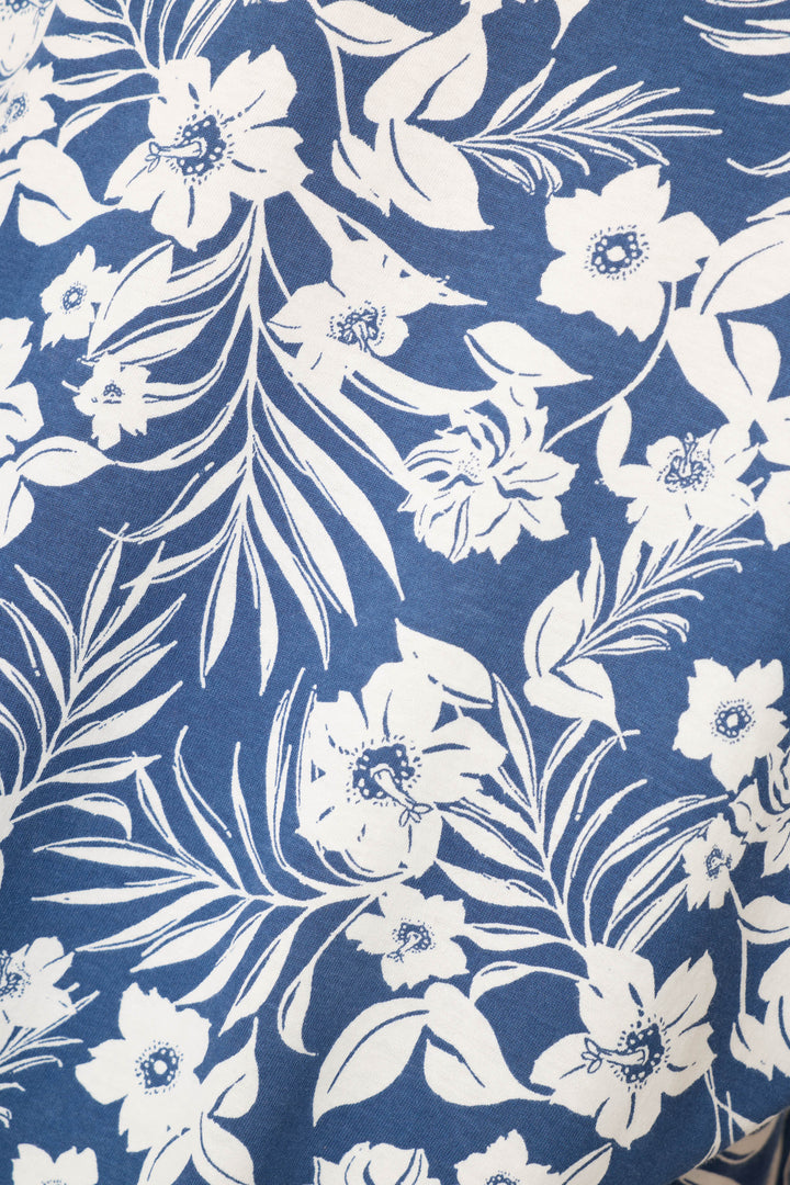 The P.J. Salvage Cotton Jersey Midnight Garden Cropped PJ Set features white floral and leaf motifs on a blue background, offering a decorative botanical design.