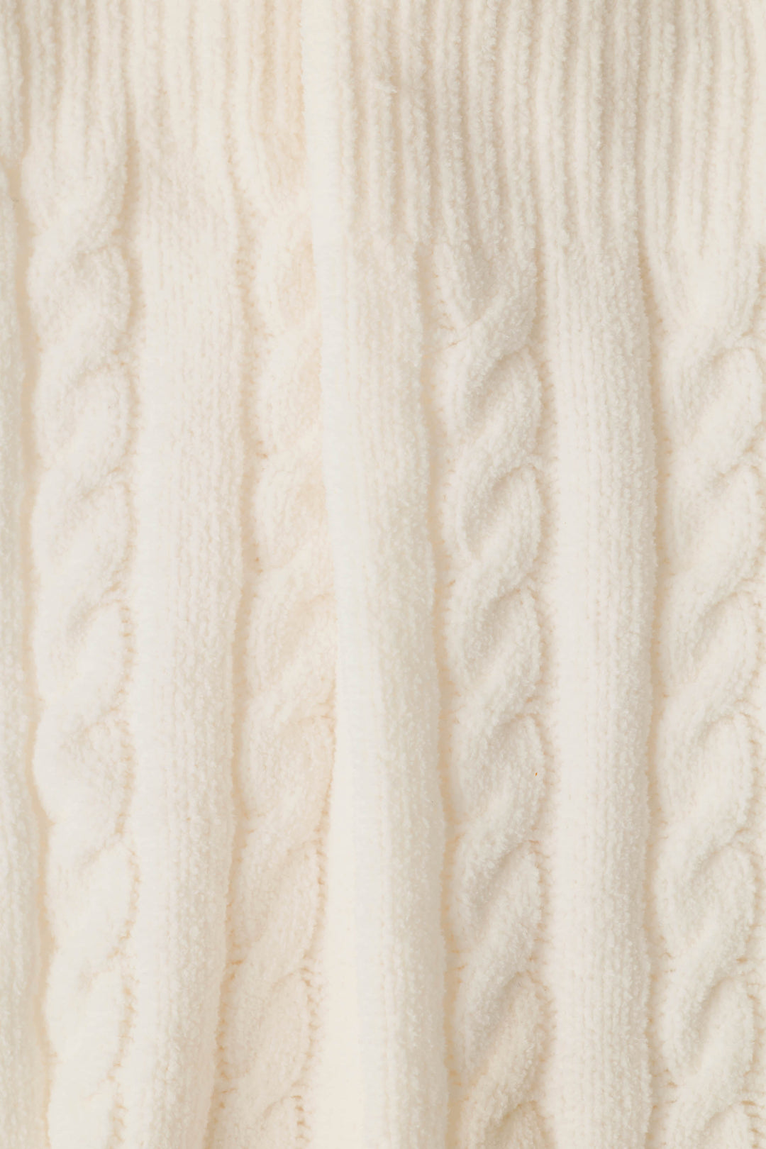 Close-up of cream-colored cable-knit fabric textured socks, showing the detailed knit pattern and soft fibers.