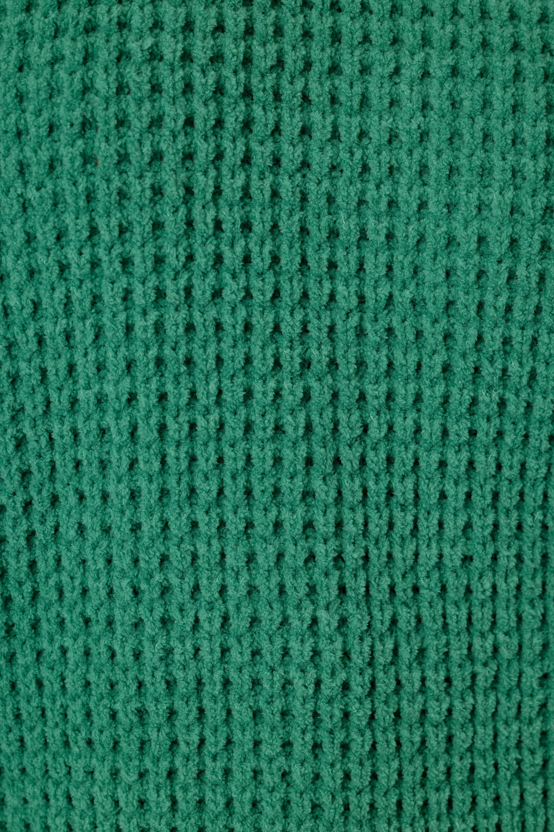 A close-up of a solid, green waffle knit fabric texture, showing the detailed pattern.