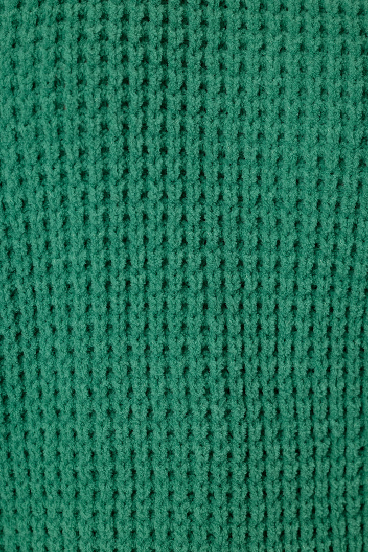 A close-up of a solid, green waffle knit fabric texture, showing the detailed pattern.