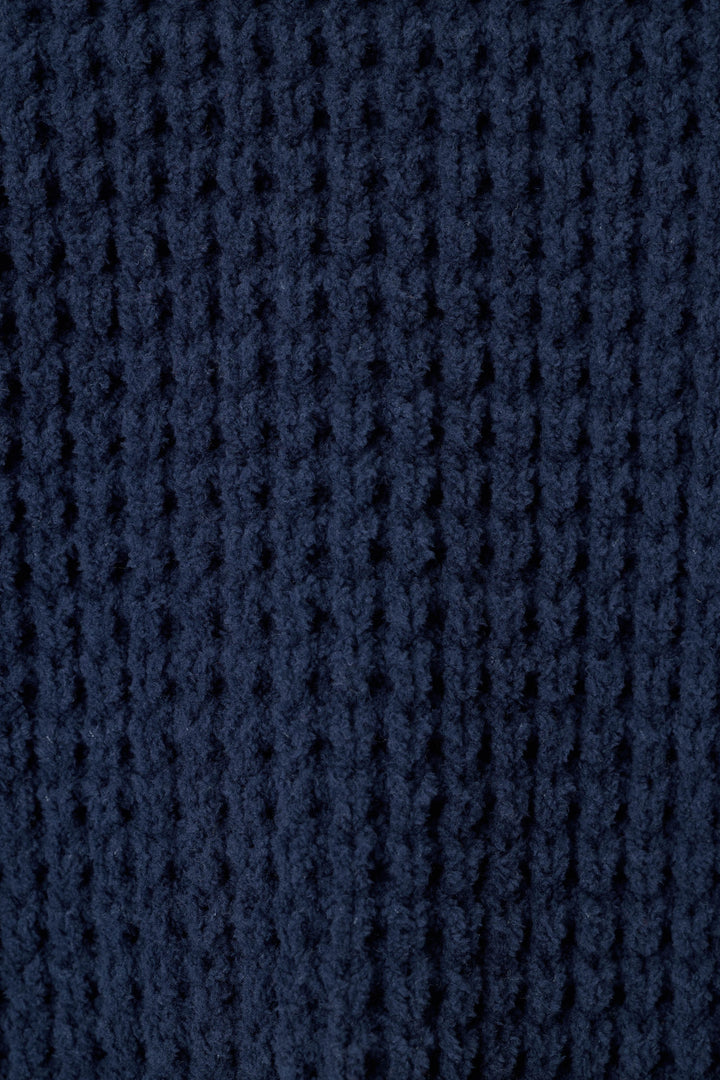 Close-up of a solid, dark navy blue waffle knit fabric texture.
