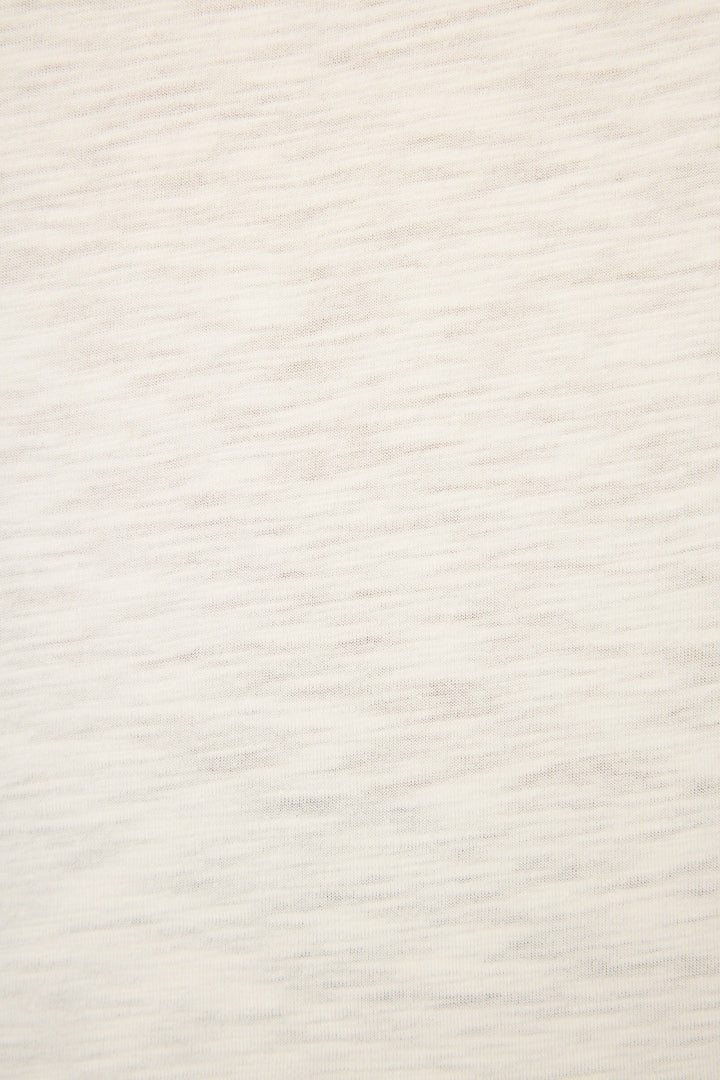 Close-up of the C'est La Vie Graphic Print Short Sleeve Top by P.J. Salvage, showing its light beige fabric with subtle horizontal texture and faint lines, emphasizing the soft, woven material without distinct patterns.
