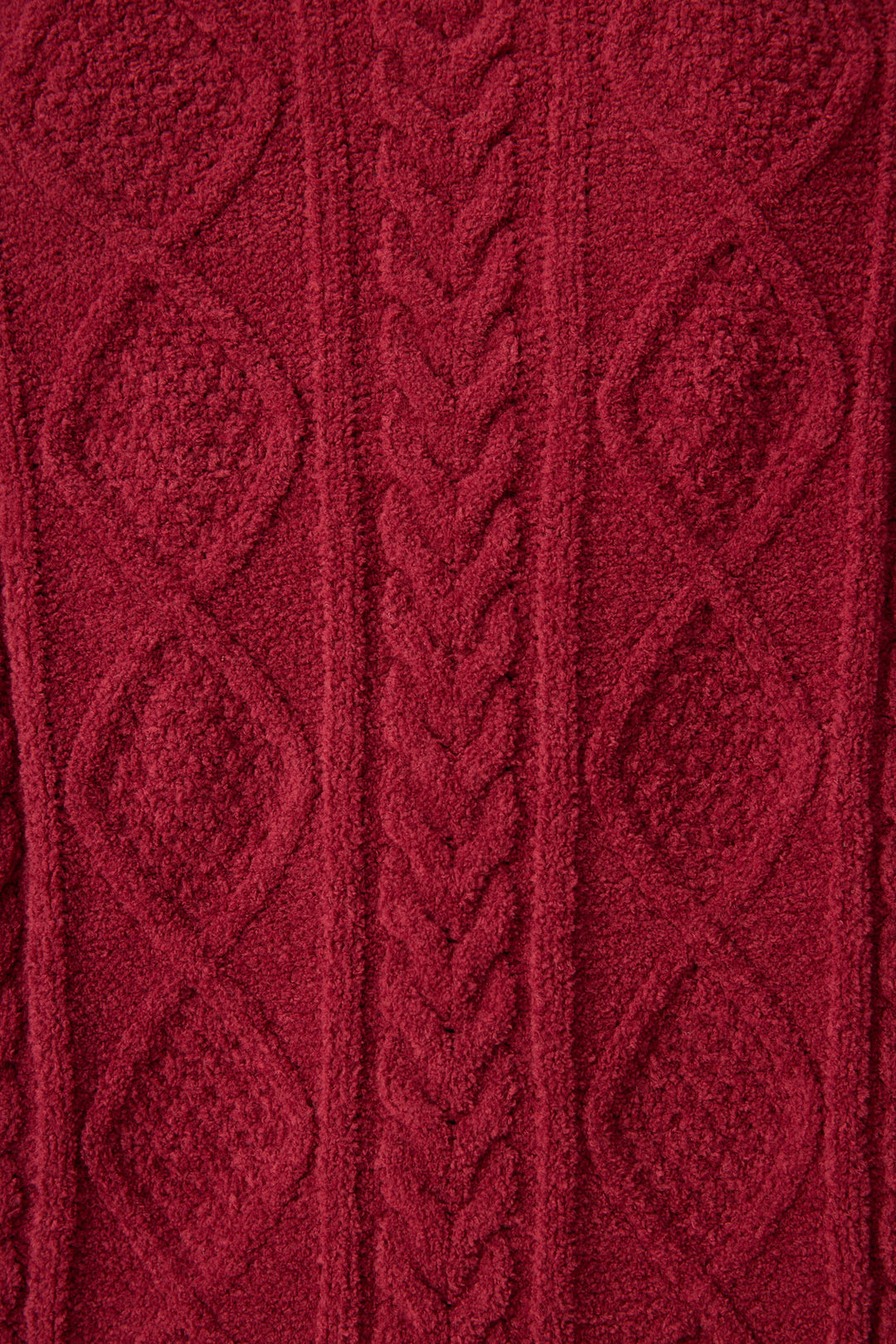 Close-up of P.J. Salvage's Chenille Cable Knit Port Slippers shows thick, soft red knit fabric with a central cable pattern and diamond designs on the sides, highlighting the cozy texture of these slippers.
