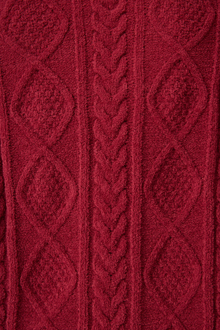 Close-up of P.J. Salvage's Chenille Cable Knit Port Slippers shows thick, soft red knit fabric with a central cable pattern and diamond designs on the sides, highlighting the cozy texture of these slippers.