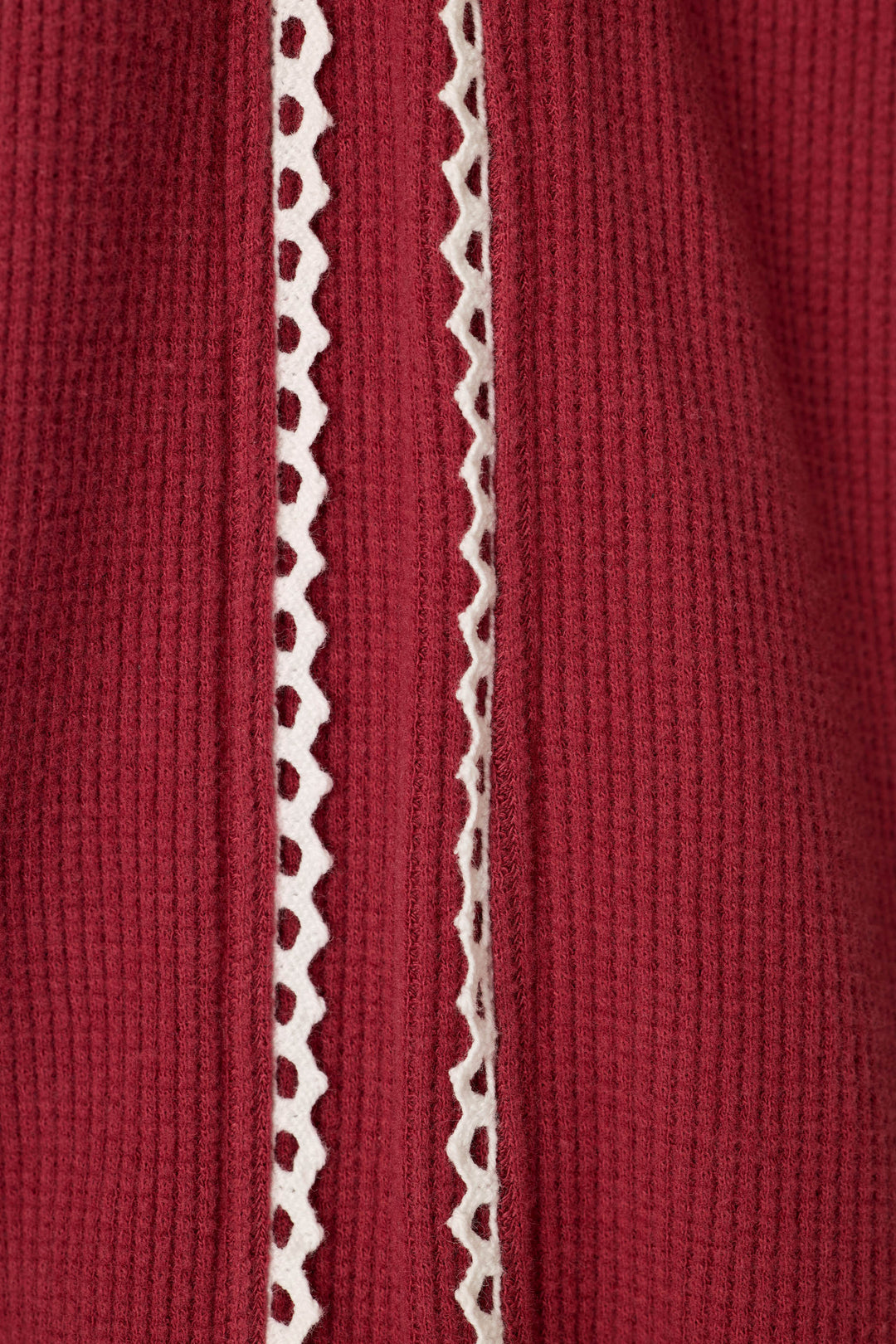 Close-up of the Weekday Waffles dark wine fabric, showcasing its red ribbed fabric with a vertical strip of white lace featuring a zigzag pattern down the center.