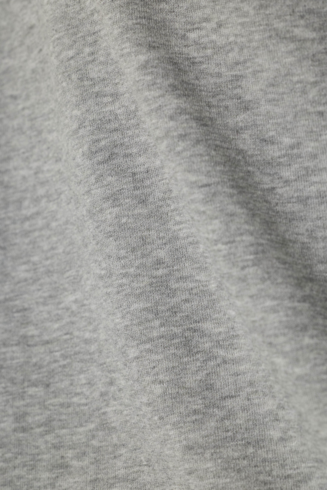 Close-up of a heather gray knit fabric texture with soft folds and ribbed stitching.