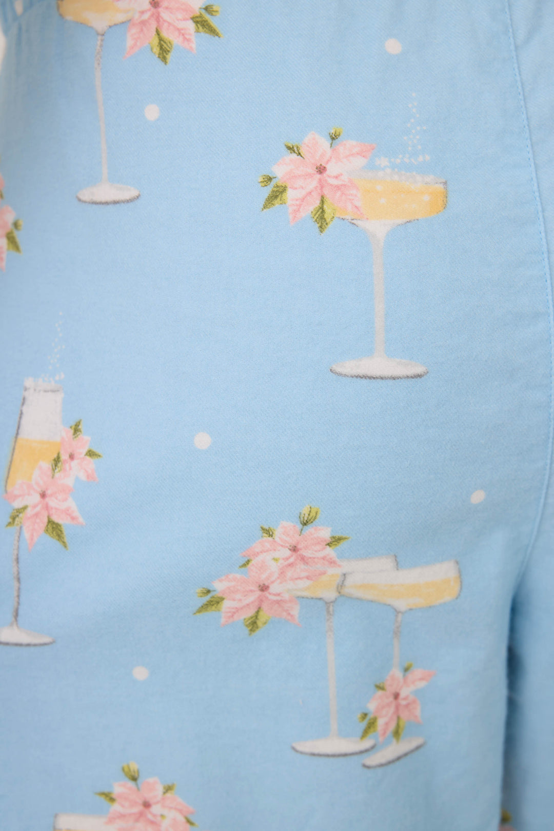 The Fizz the Season Open Leg Flannel Pants by P.J. Salvage feature light blue fabric decorated with champagne glasses, pink poinsettia flowers, and small white dots throughout.