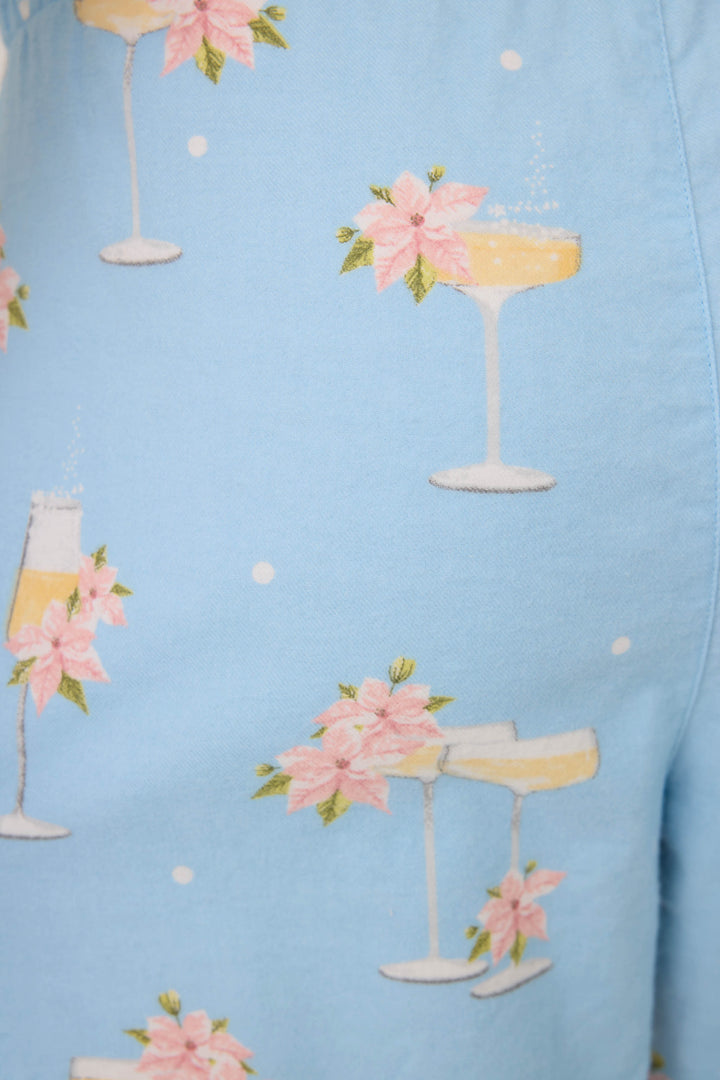 The Fizz the Season Open Leg Flannel Pants by P.J. Salvage feature light blue fabric decorated with champagne glasses, pink poinsettia flowers, and small white dots throughout.