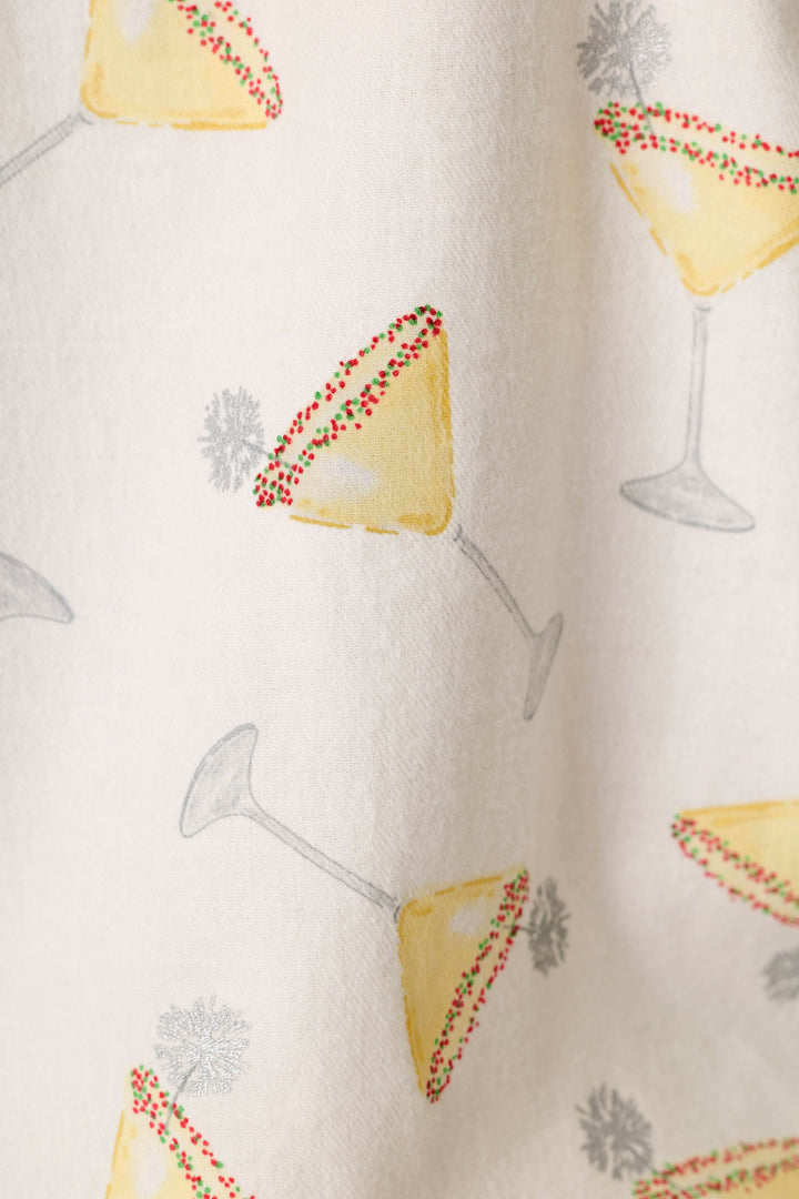 A close-up of a cream-colored fabric with a repeating pattern of martini glasses rimmed with red and green sprinkles, accented with small silver sparklers.