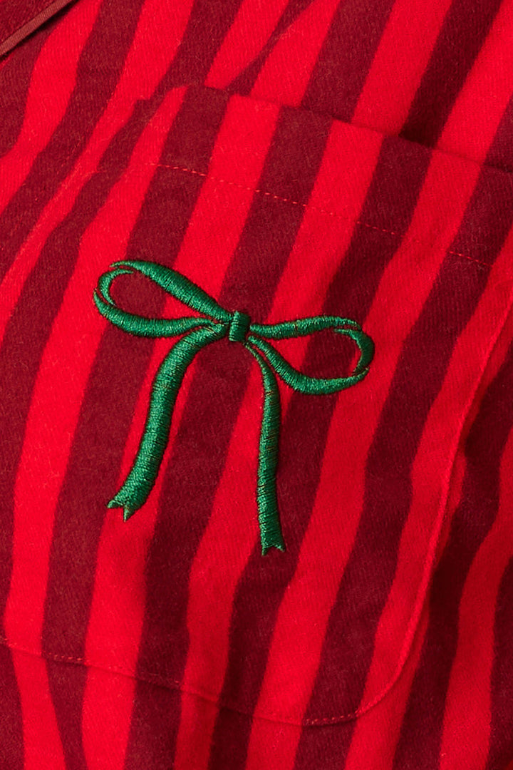 A close-up of the Icon 3-Piece Long Sleeve Flannel PJ Set by P.J. Salvage showcasing red fabric with vertical dark red stripes and a small green embroidered bow on the chest pocket.