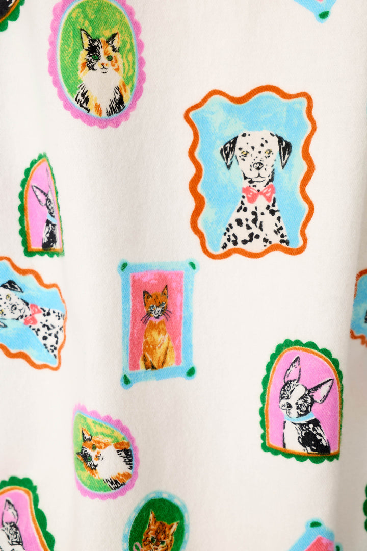 A close-up of a white fabric featuring a colorful cartoon dog and cat print of cat & dog portraits, all in different shaped frames in different colors like pink, blue, green, orange, and purple.