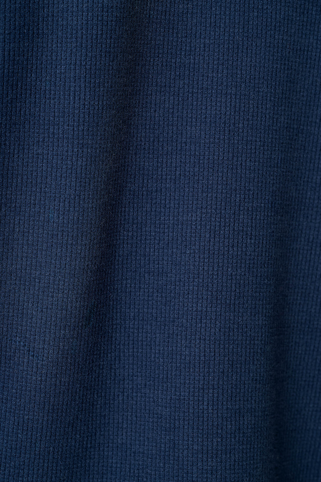 A close-up of a dark navy blue knit fabric with a waffle texture.