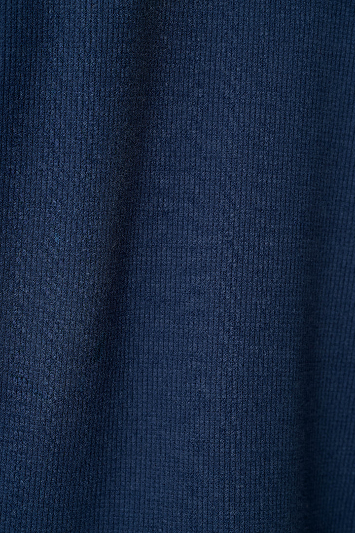 A close-up of a dark navy blue knit fabric with a waffle texture.