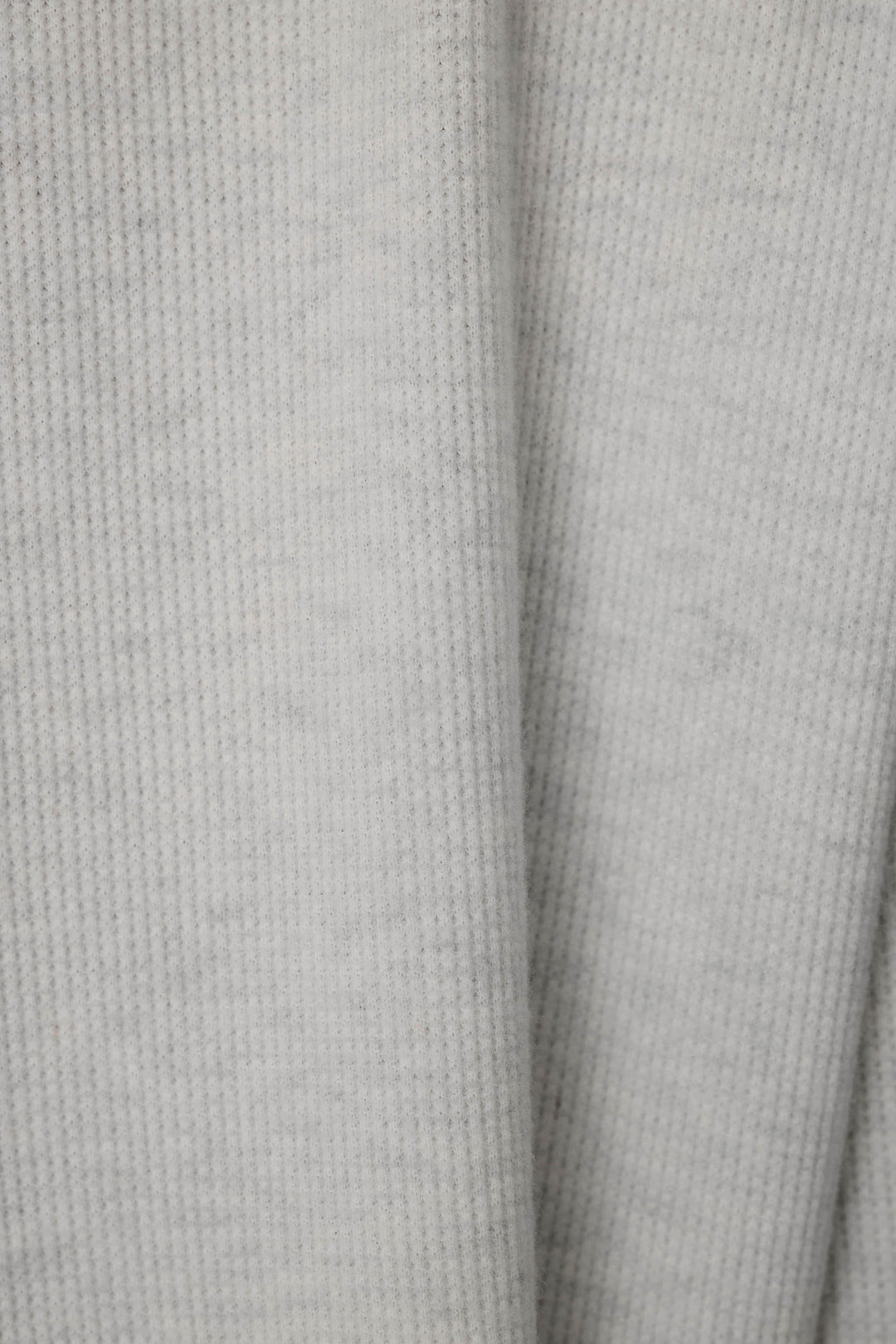 Close-up of a light gray knit fabric with a soft waffle texture.