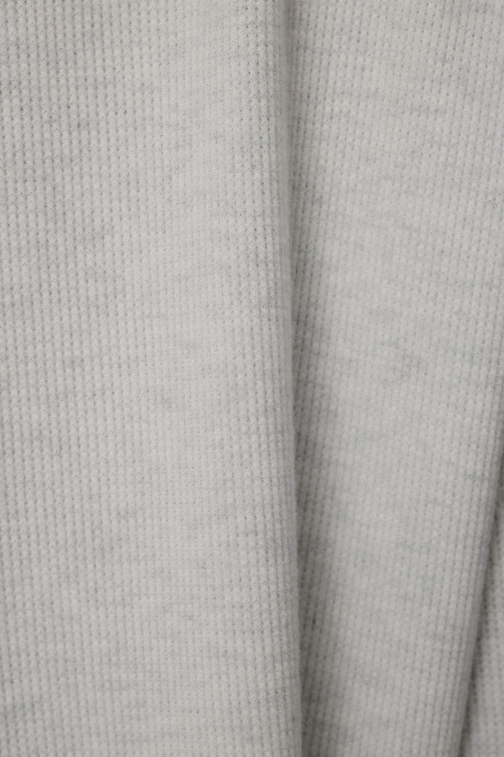 Close-up of a light gray knit fabric with a soft waffle texture.