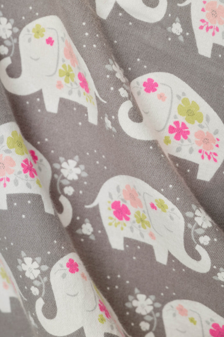 A close-up of fabric featuring a repeating pattern of white elephants decorated with pink, green, and yellow flowers on a medium gray background.