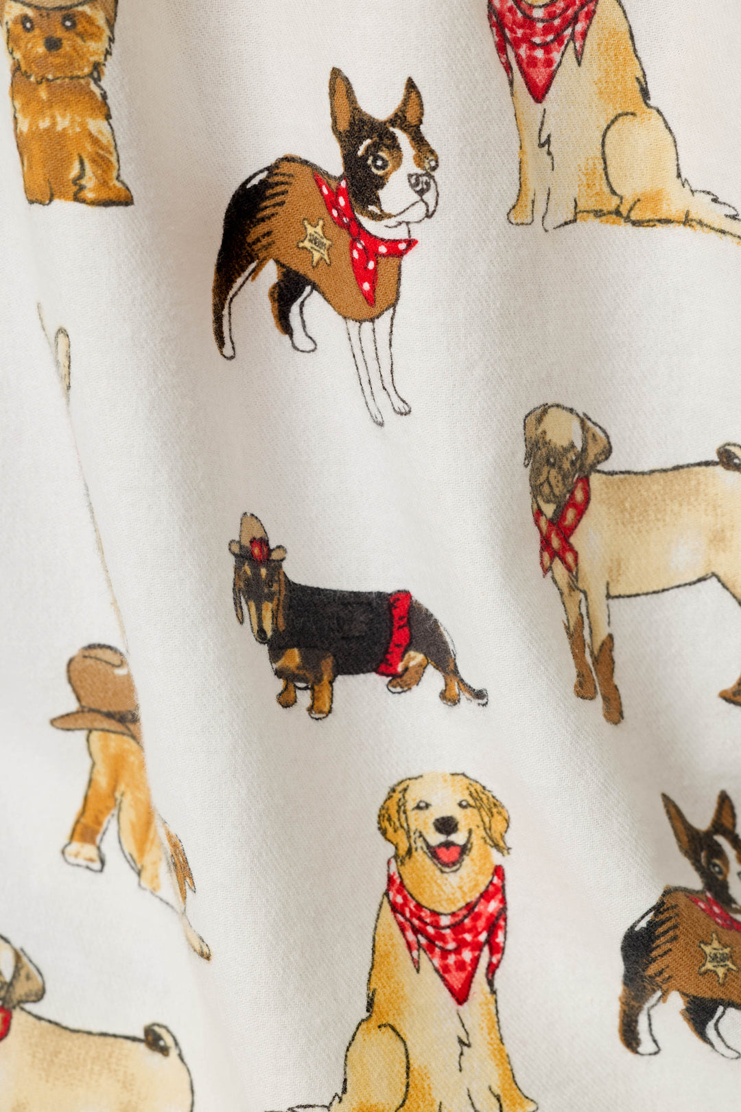 A close-up of a white fabric printed with illustrated dogs wearing cowboy hats and red bandanas, showing the repeating pattern clearly.