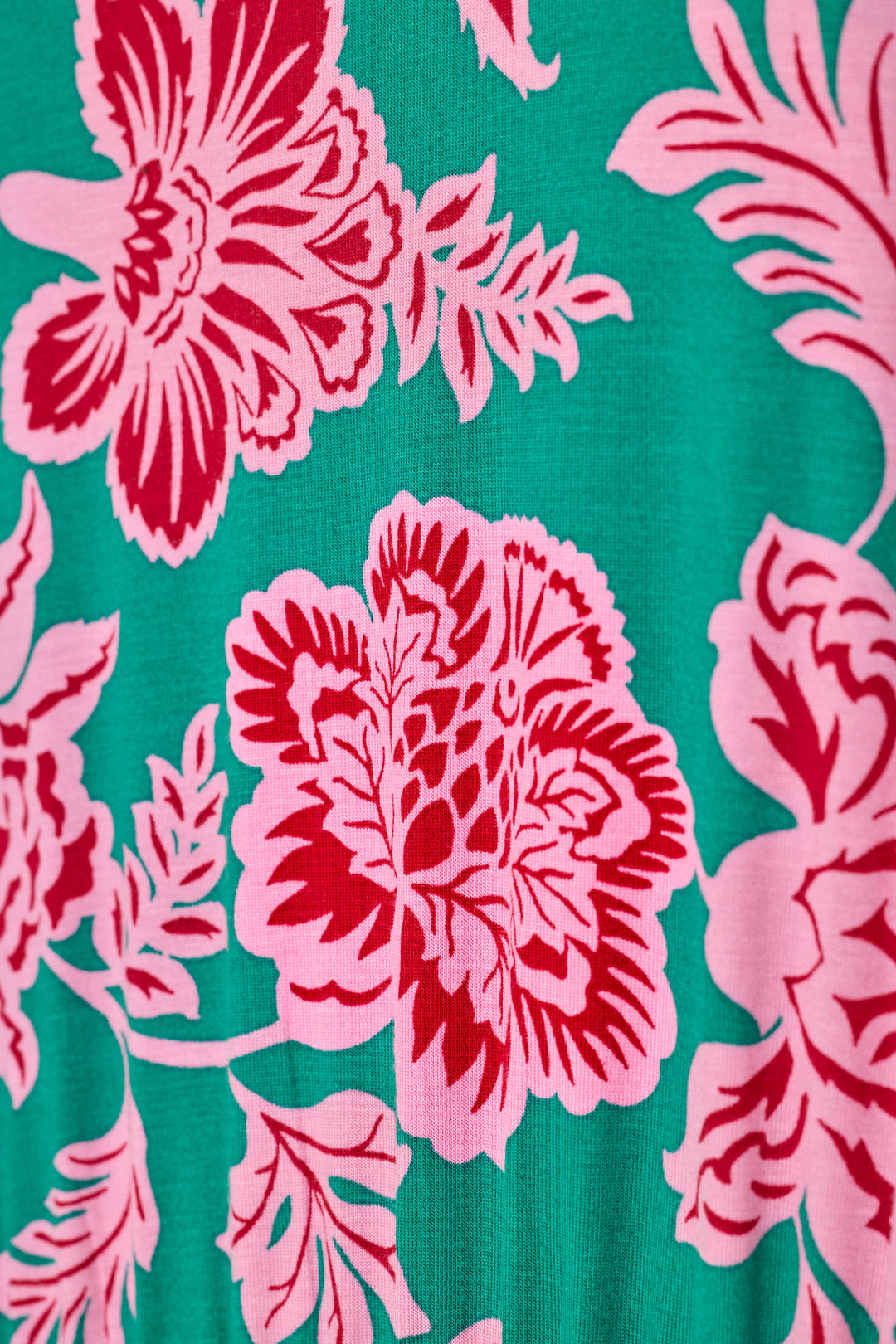 A close-up of a vibrant floral pattern featuring large pink flowers and leaves on a bright green background.