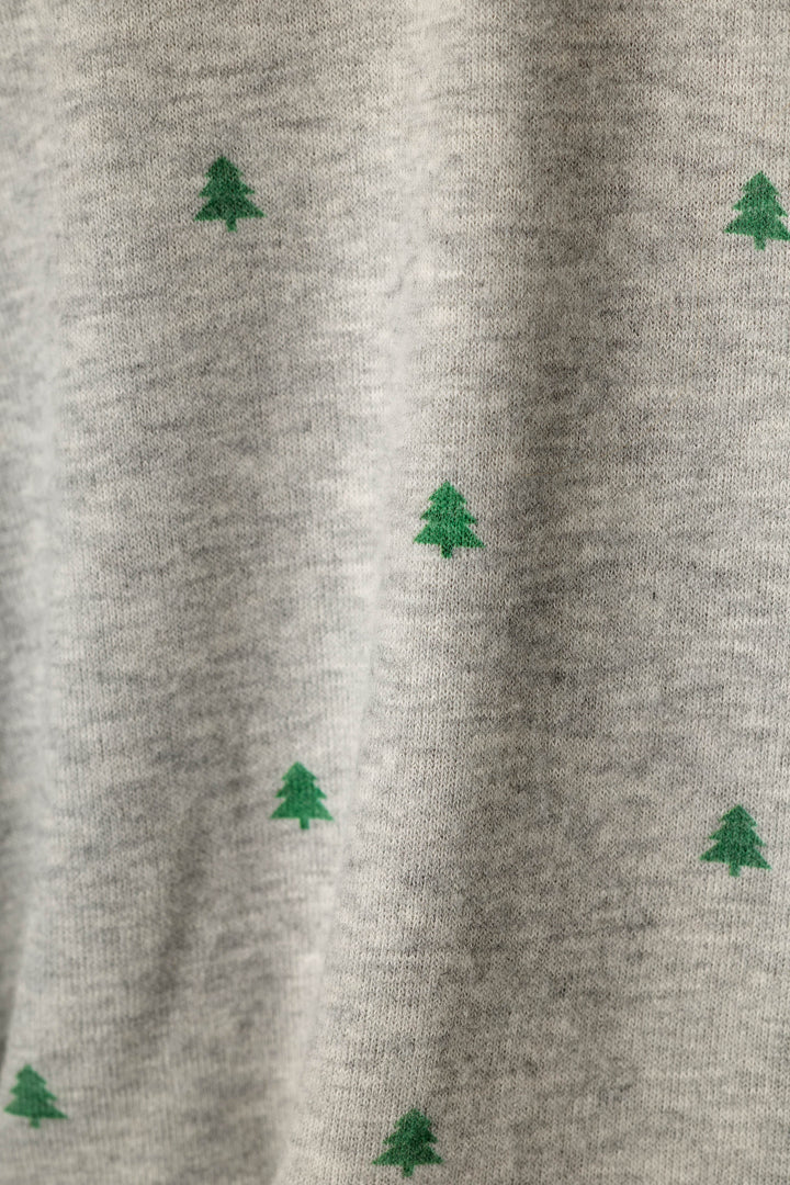 Close-up of a heather gray knit fabric with small green pine tree motifs scattered across it.