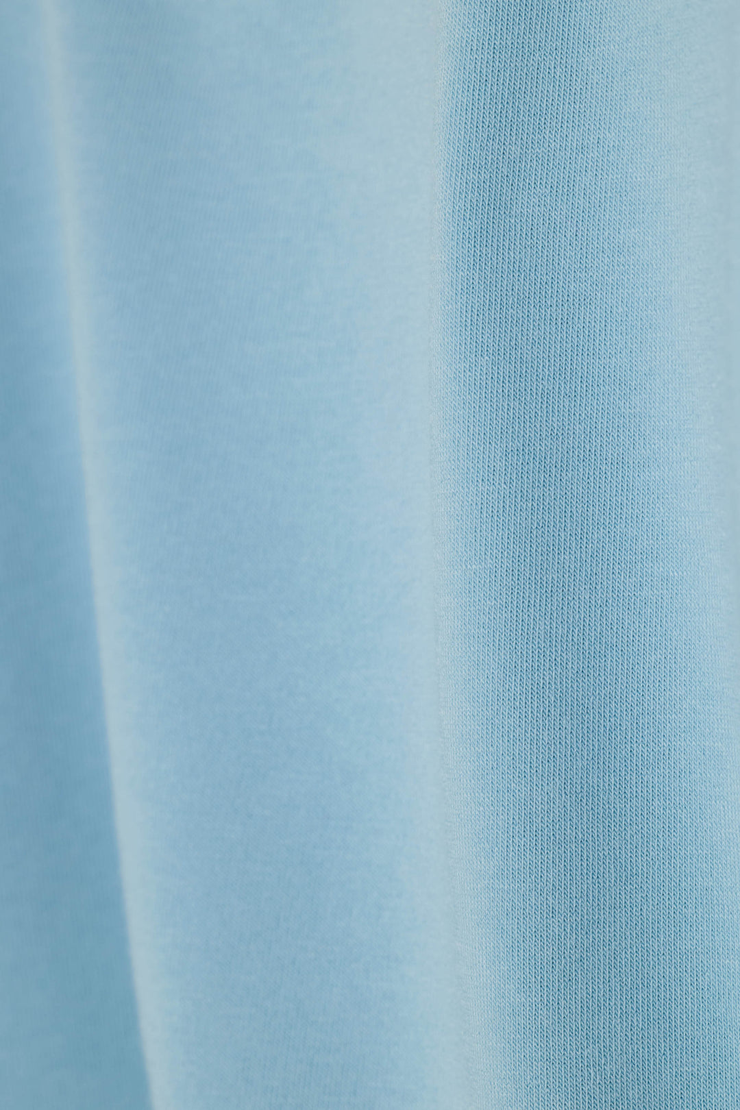 A close-up of light blue ribbed knit fabric with soft vertical folds and a smooth texture.