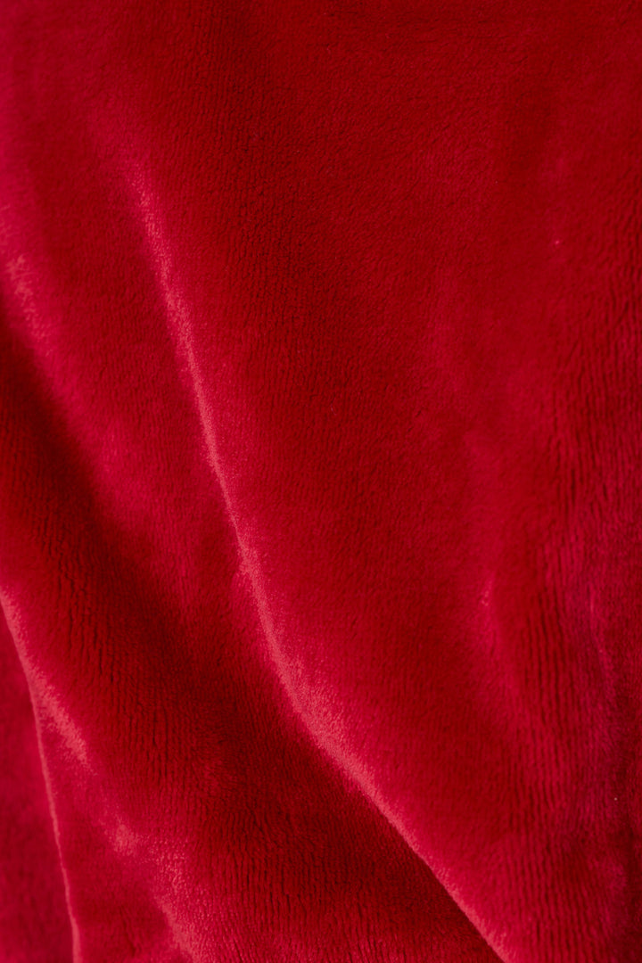 A close-up of a plush, textured red fabric with soft folds and a velvety sheen.
