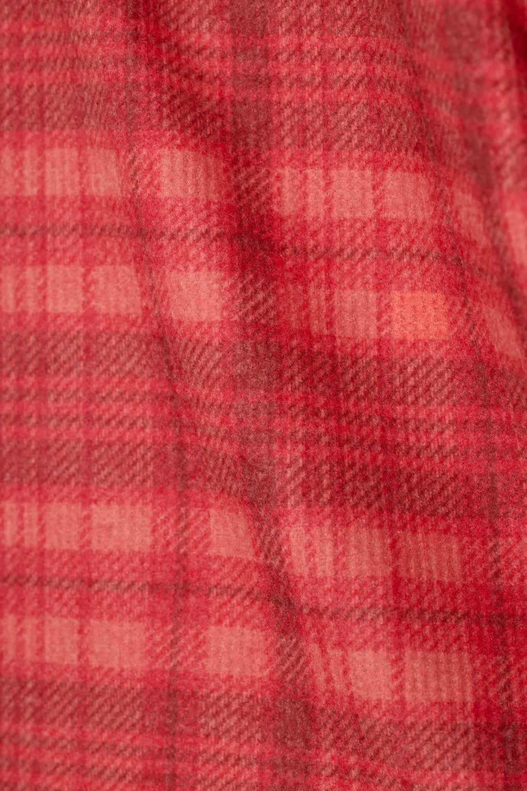 A close-up of a red plaid fabric texture with a soft, woven appearance.