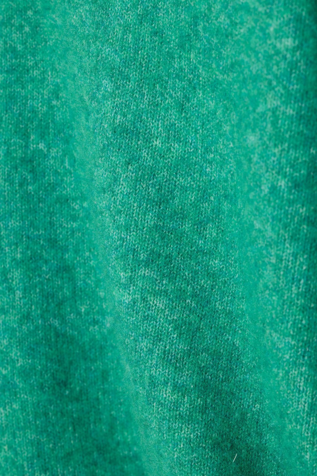 A close-up of a fuzzy textured green knit fabric.