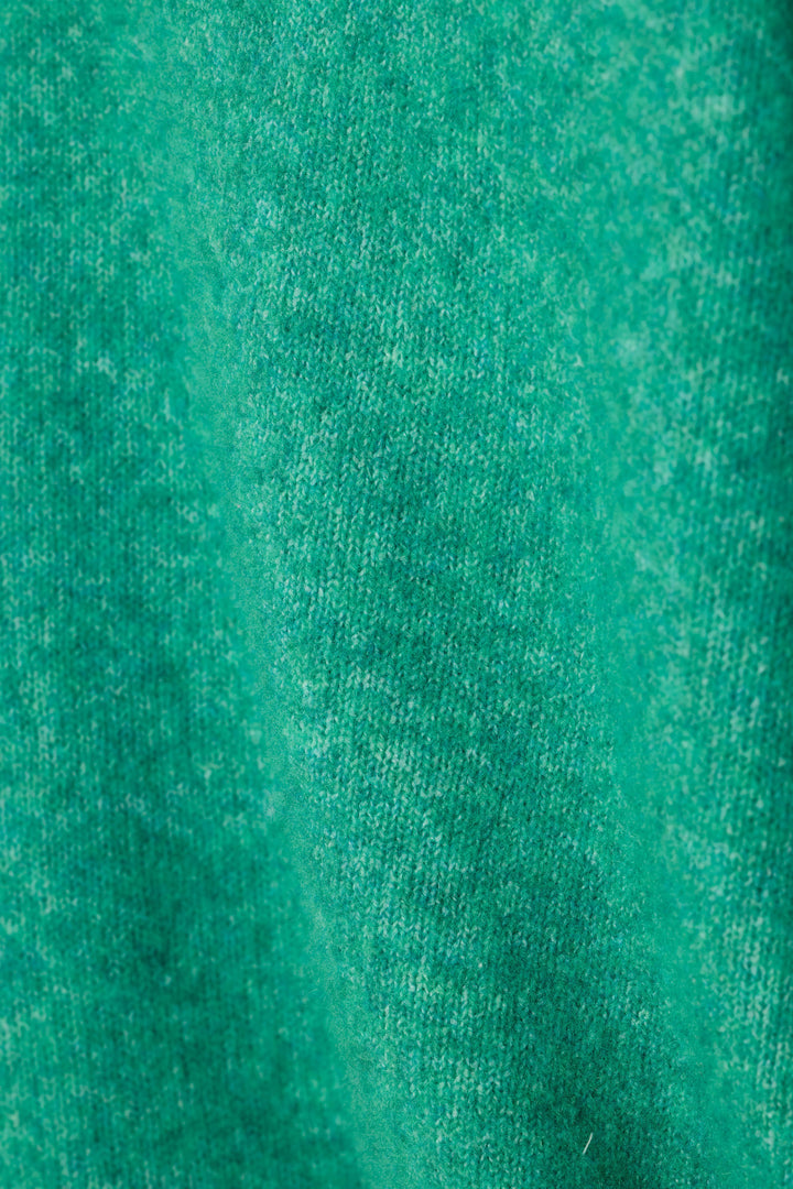 A close-up of a fuzzy textured green knit fabric.