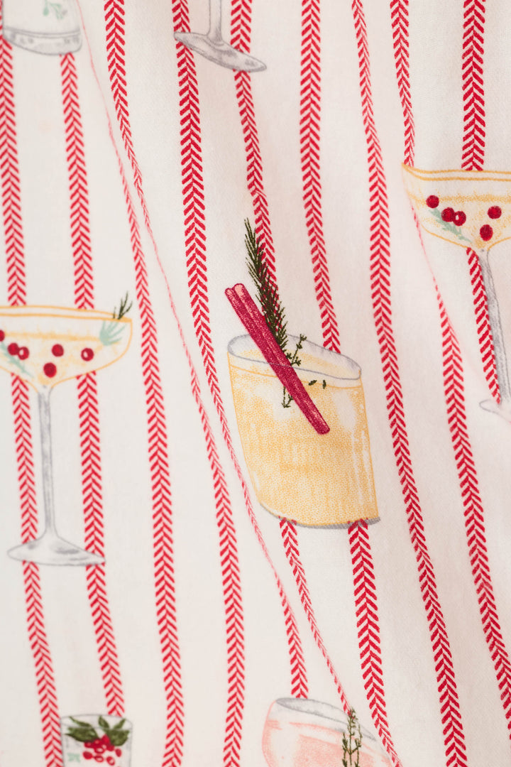A close-up of a patterned fabric featuring vertical red herringbone stripes with illustrated cocktail glasses and a drink garnished with a pink straw and green sprig.