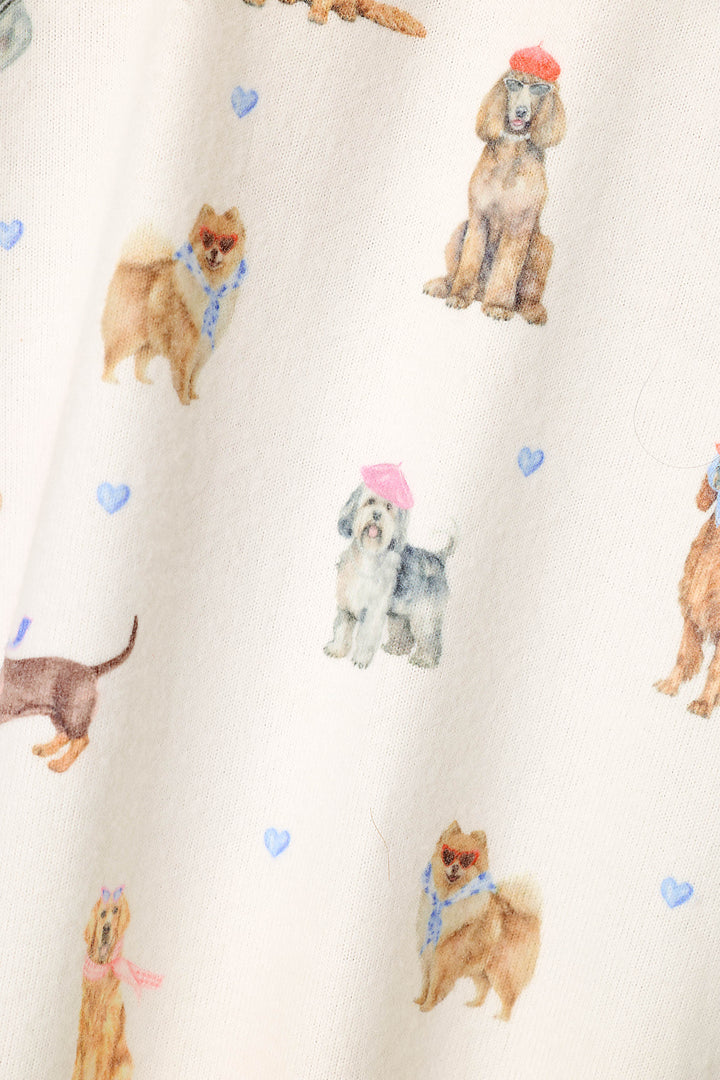 Close-up of a cream-colored fabric with a watercolor print of various dog breeds, including Pomeranians, Poodles, and Shih Tzu dogs, some wearing pink and red hats and blue scarves, accented by small blue hearts.
