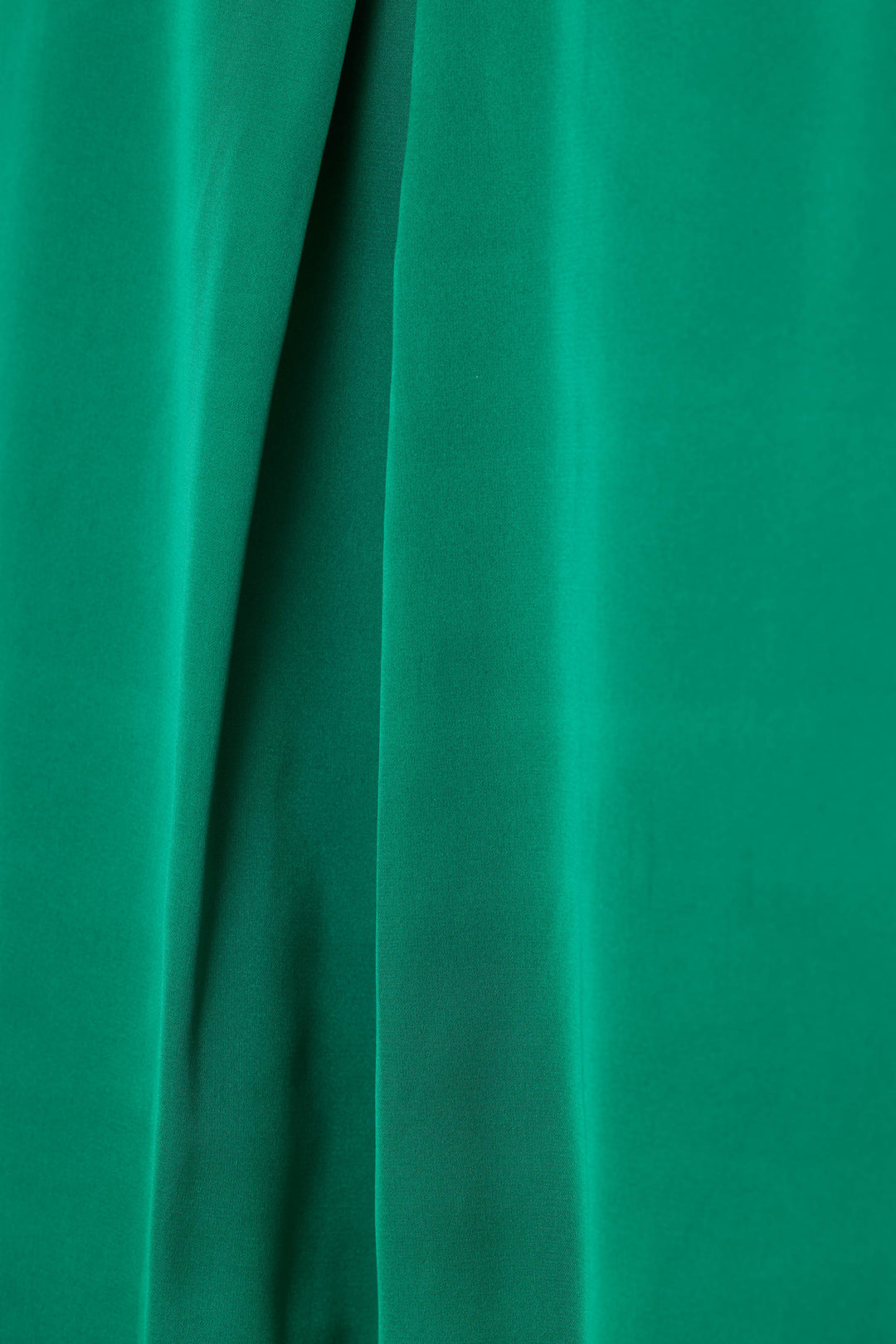 A close-up of emerald green satin fabric with soft vertical folds and a smooth texture.