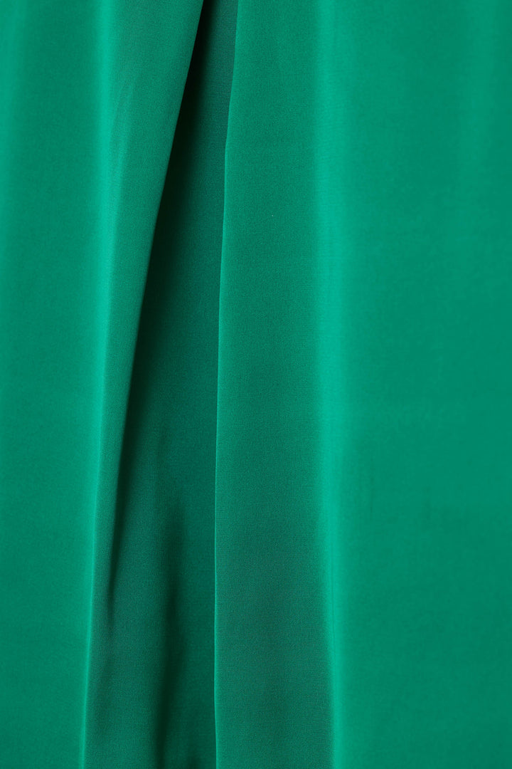 A close-up of emerald green satin fabric with soft vertical folds and a smooth texture.