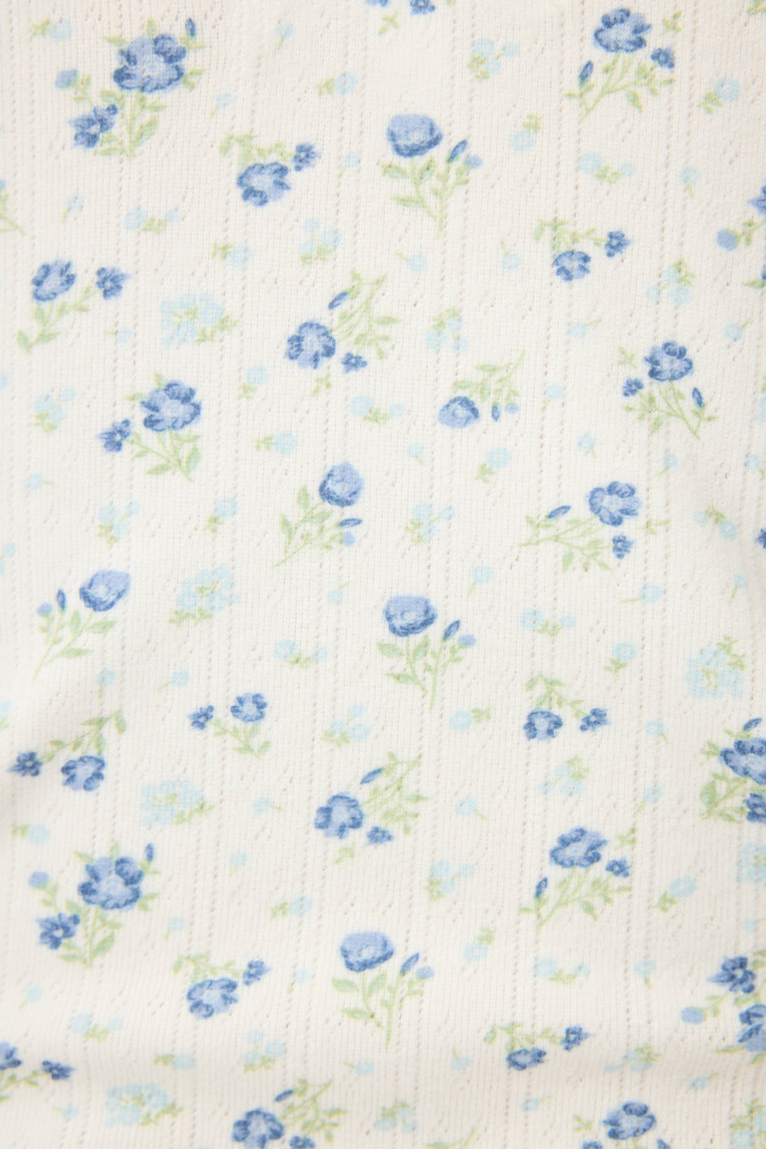 The P.J. Salvage More Amour Ditsy Floral Long Sleeve Pointelle Top features white ribbed fabric with a delicate scatter of small blue flowers and green stems, varying in size and density for a charming, textured look.
