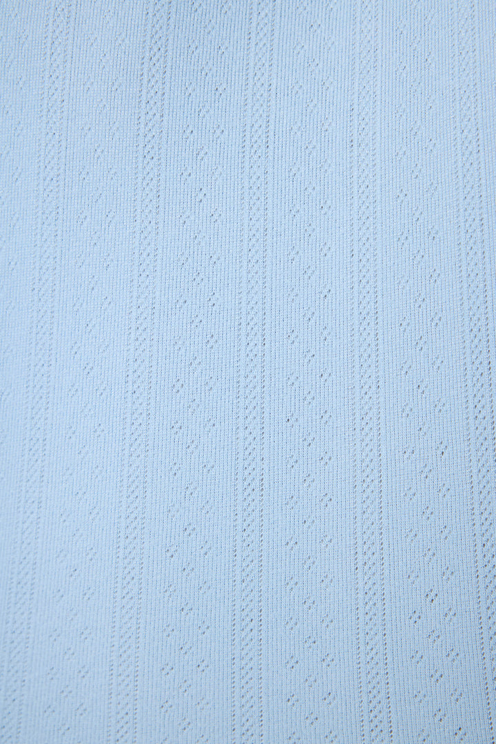 The P.J. Salvage More Amour Blue Dream Pointelle fabric features light blue fabric with a subtle textured pattern of vertical lines and evenly spaced small diamond shapes.