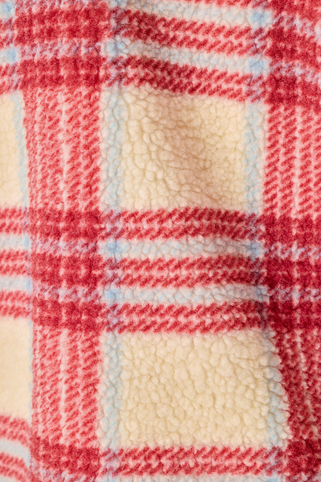 Close-up of a plaid fleece fabric with red, cream, and light blue stripes.