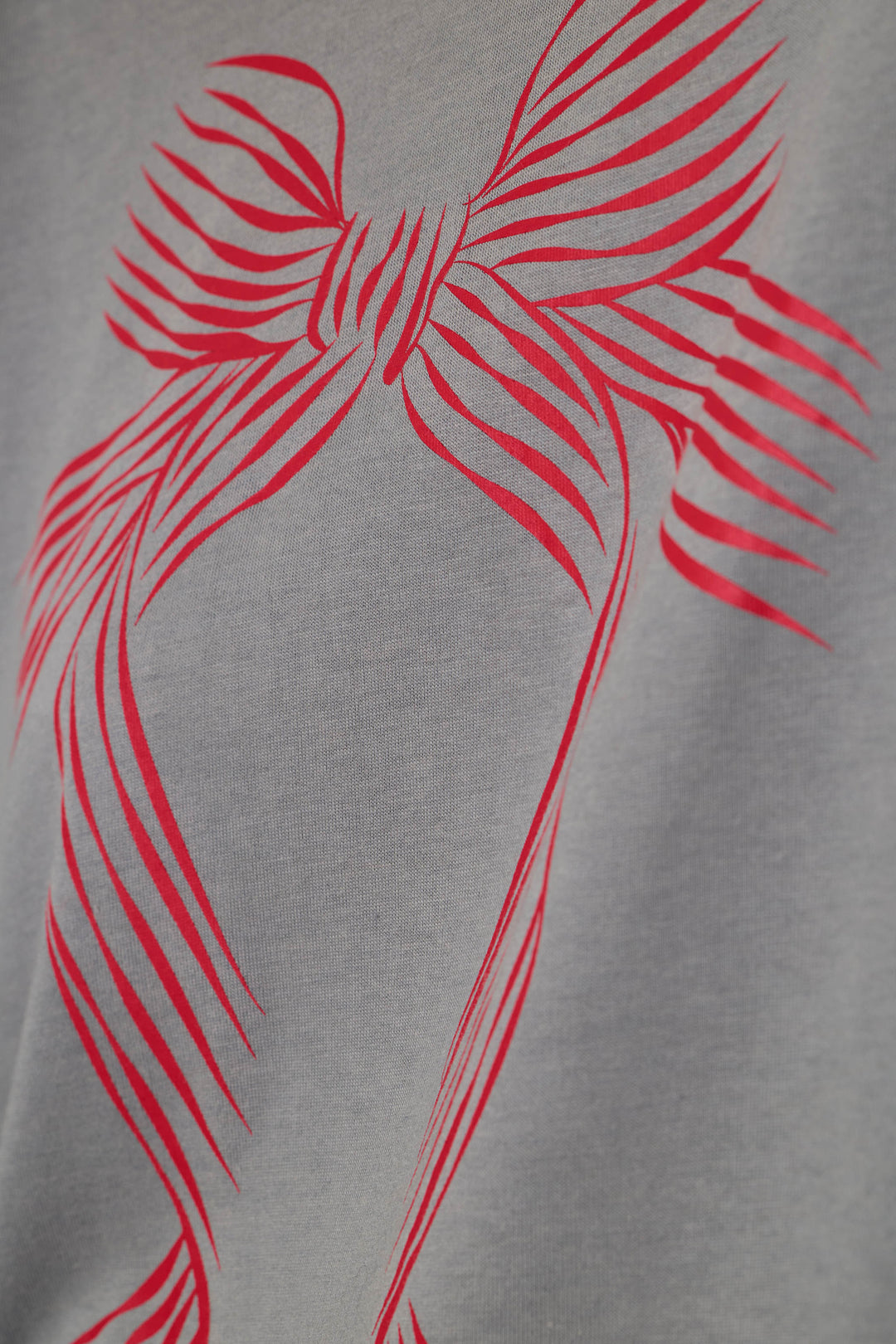 Close-up of a light gray heathered fabric with a bold red graphic print of a stylized ribbon.