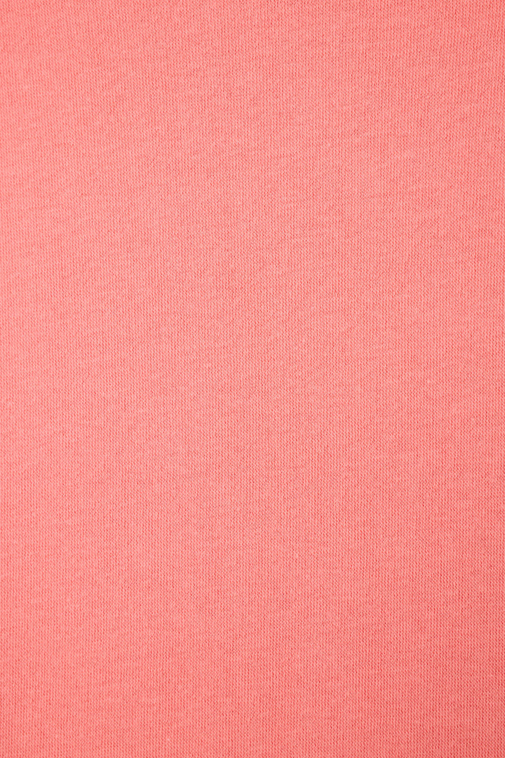 A close-up of the Paloma Mama Cocktails Please Graphic Sweatshirt by P.J. Salvage shows its sunset rose fabric with a smooth, fine knit texture and an even, uniform finish without visible patterns or irregularities.